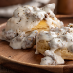 Closeup of biscuits and creamy sausage gravy on a wooden plate